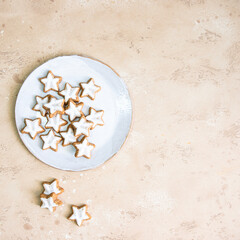 Fototapeta na wymiar Top view of star shape ginger cookies with sugar icing onwhite plate on beige background.