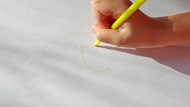 sun hand draws with a felt-tip pen on a white sheet of paper. childrens creativity, naive drawing.