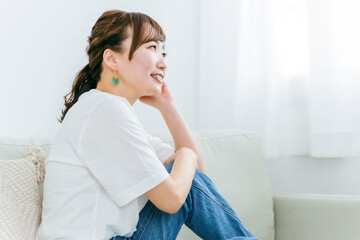 家でリラックスしてソファでくつろぎながら幸せを感じる笑顔の日本人女性の横顔

