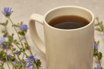 chicory drink in a coffee mug next to chicory flowers