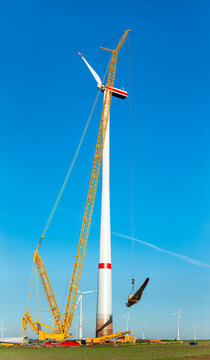 Construction work of wind turbine. crane is holding, grabing a blade of a wind turbine. Building and assembling a windturbine. Green energy, ecology and CO2-footprint reduction concept. Wörrstadt 