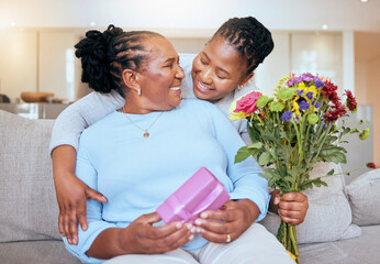Black woman, mothers day and hug with flowers on sofa for love, box or gift to mom in home. Woman, bouquet and senior mama with wow, smile or happy for surprise, celebration or birthday on couch - obrazy, fototapety, plakaty