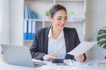 Portrait of beautiful smiling young entrepreneur businesswoman holding cup of coffee and working on laptop computer at office. Panoramic background.
