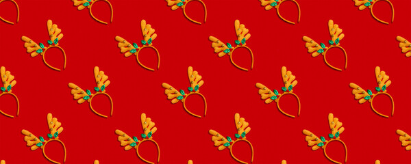 Seamless New Year and Christmas pattern with headbands with deer antlers on a red background