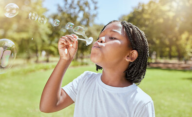 Park, child and black girl blowing bubbles enjoying fun time alone outdoors, joy and childhood development. Happy, freedom and kid learning and playing with soap bubble toy or wand and relax on grass - Powered by Adobe