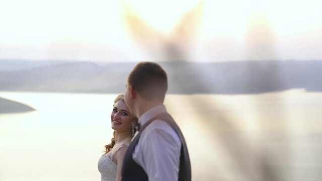 Bride and groom walking down the beach at sunset, refocusing on wedding rings.
