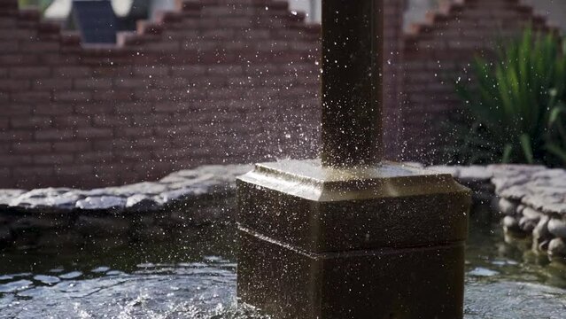 Decorative waterfall on natural stones with eagle statue fnd blue sky. Slowmo