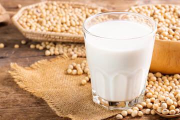 Soy milk in a glass with soybeans on a wooden table Organic breakfast, high protein, healthy, agricultural products, vegetarian