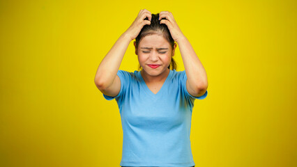 Young nervous woman scratches her head, hair itching on yellow background - obrazy, fototapety, plakaty