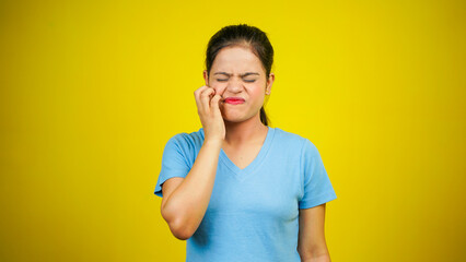Young woman scratching face or cheek, isolated over yellow background. Annoying itching and rashes...