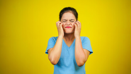 Young woman scratching face or cheek, isolated over yellow background. Annoying itching and rashes...