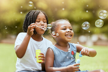 Black kids, children and blowing bubbles at park, having fun and bonding. Girls, happy sisters and...