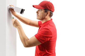 Profile shot of a young man installing a security camera