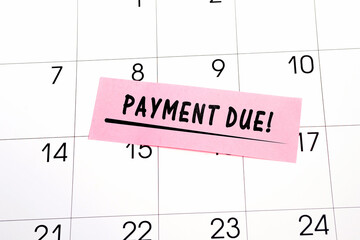 The phrase Payment Due written in black text on a pink sticky note posted to a calendar page as a...