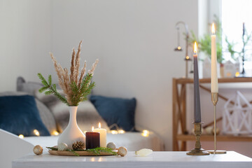 burning candles with christmas decor in white cozy interior