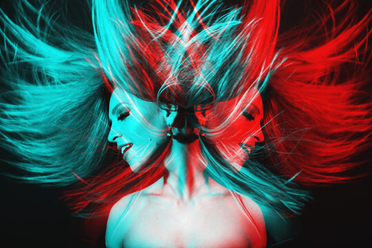 Fashion concept. Portrait of beautiful woman with flying hair in red and blue color split effect style. Futuristic looking style. Image contains motion blur. Model with happy facial expression