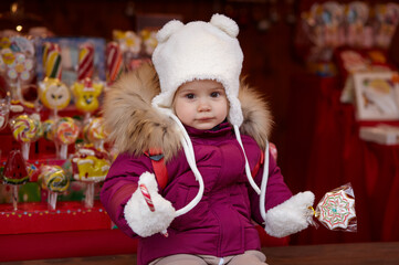 Baby girl are walking around the city on Christmas and New Year holidays. Little child having fun outdoors