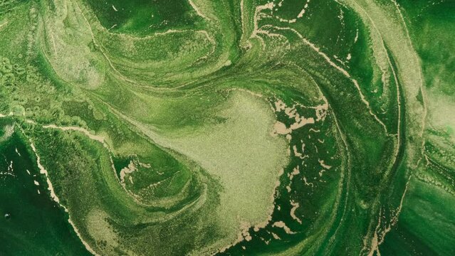 Green golden paint swirl, moving abstract background. Spread, flow shiny green yellow ink. Fluid art backdrop. Dynamic art green fluid paints. Golden emerald flowing glitter texture. Watercolor liquid