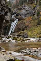 A waterfall in an autumn valley. Golden leaves and silky waters