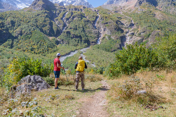Two tourists are going to climb up the mountain to the waterfalls, inspect the area.