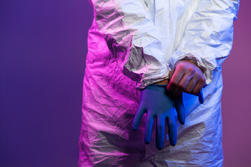 Coronavirus covid-19 pandemic. Doctor scientist wearing protective biological suit and mask due to global healthcare epidemic warning and danger background in blue and pink neon lights background.