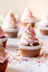 Close-up of the frosted carrot cupcake with buttercream and colorful birthday sprinkles
