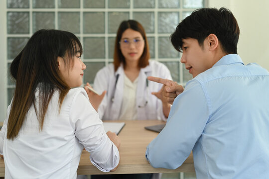 Back view of young couple arguing during family therapy counselling session with psychologist in clinic