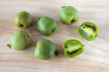 Mini kiwi actinidia on a wooden board. A cut up little fruit. Selective focus.
