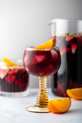 Glass of traditional red sangria with red wine, ice and fruits, light background