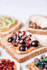 Various kind of open sandwiches with berries and fruits. Made from bread, such as wholegrain, rice crakers, crispbreads and different nut butter, such as peanut, crunchy cashew and almond butter