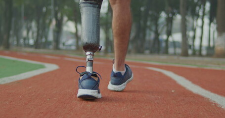 One disabled athlete walks outdoors with prosthetic leg. Male person with disability