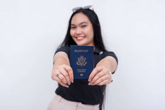 A happy asian woman proudly shows her newly acquired US passport. Isolated on a white background.