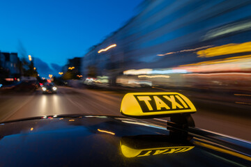 Illuminated taxi sign on moving car roof at night