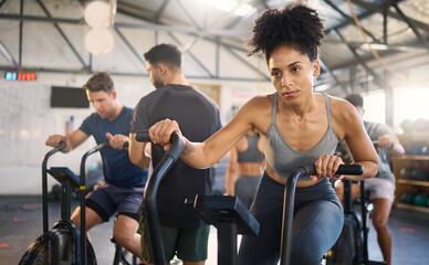 Fitness, class and bike workout of a black woman in a cycling, training and exercise studio. Bicycle sport, gym wellness and sports health club with a person on a machine with athlete motivation