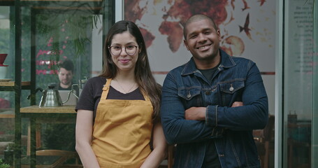 Two happy employees of local small business shop. Young diverse millennials entrepreneurs posing together at camera with arms crossed