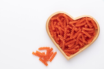 Red lentil fusilli pasta in a heart shaped wood bowl.