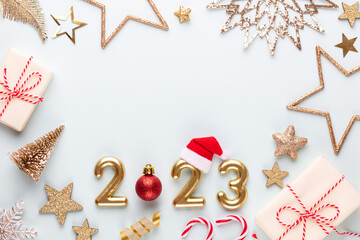 Fototapeta na wymiar New year 2023 number, golden digits and santa hat over blue background.