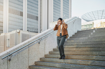 Music, stairs and city with a business black woman walking outdoor while using headphones for...
