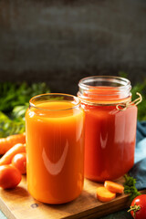 Vitamins drinks juice carrot and tomato, healthy lifestyle. Tomato and carrot juice in a glasses and fresh tomatoes on a stone tabletop. Copy space.
