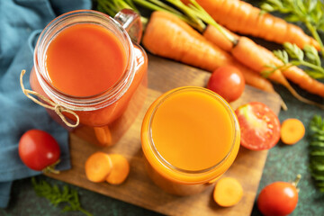 Vitamins drinks juice carrot and tomato, healthy lifestyle. Tomato and carrot juice in a glasses and fresh tomatoes on a stone tabletop.