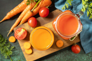 Tomato and carrot juice in a glasses and fresh tomatoes on a stone tabletop. Vitamins drinks juice...