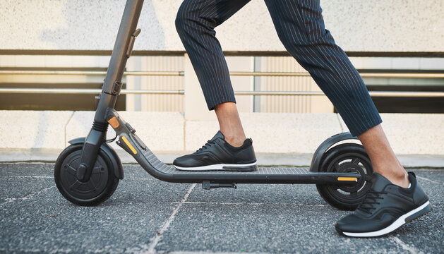 Electric scooter, fashion and travel on a city street with black sneakers, energy and modern tech for eco friendly transportation. Future, hipster and energy of urban male legs on e scooter vehicle