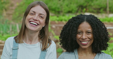 Obraz premium Two happy diverse women standing outdoors in green field laughing and smiling. Joyful people portrait faces in agriculture countryside