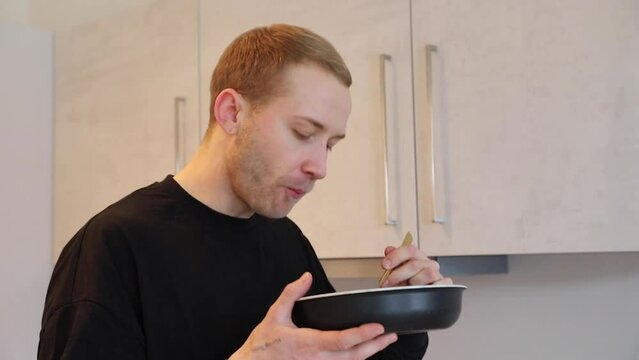 Young man eating in the kitchen 