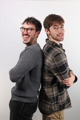 deux amis ou frères sont debout, dos à dos et rient dans un moment de complicité. Isolé sur fond blanc