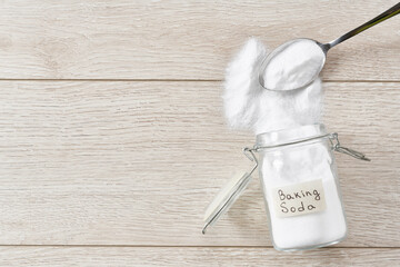 Baking soda spill out of a glass storage jar  on a white wooden table,top view.
