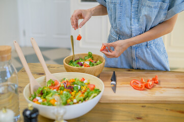 Crop woman preparing healthy salad in kitchen