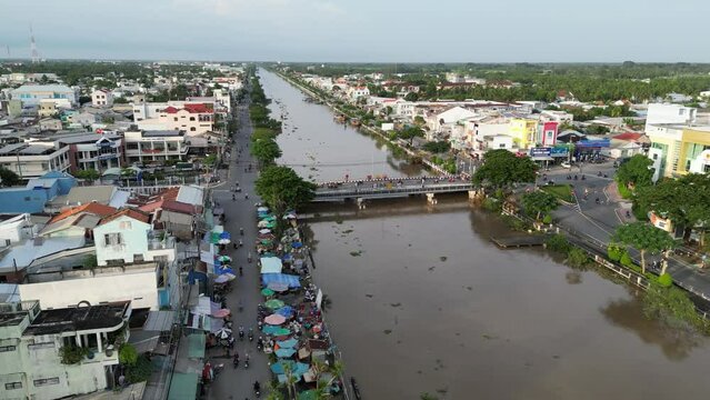 Aerial drone footage above Song Long Binh canal in Tra Vinh city, Vietnam. Camera is moving foward above the canal along the streets and houses.
