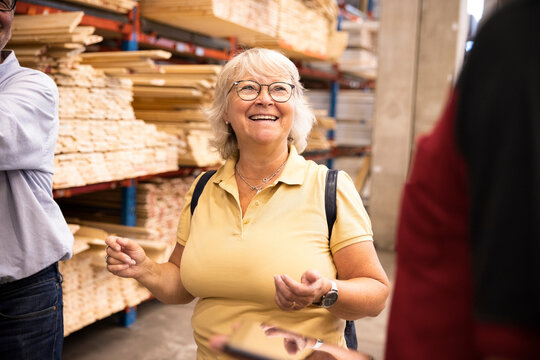 Happy senior woman wearing eyeglasses looking at saleswoman in hardware store