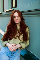 Young woman with long ginger hair outdoors in city. Young woman face with freckles